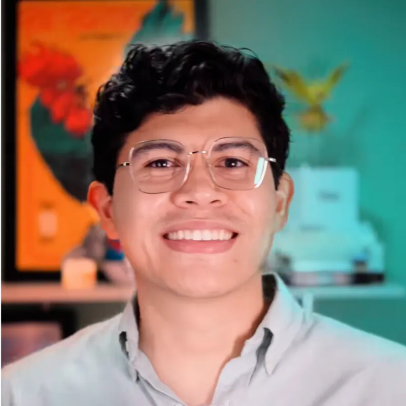 Rodrigo Puente, smiling, wearing glasses and a light grey shirt